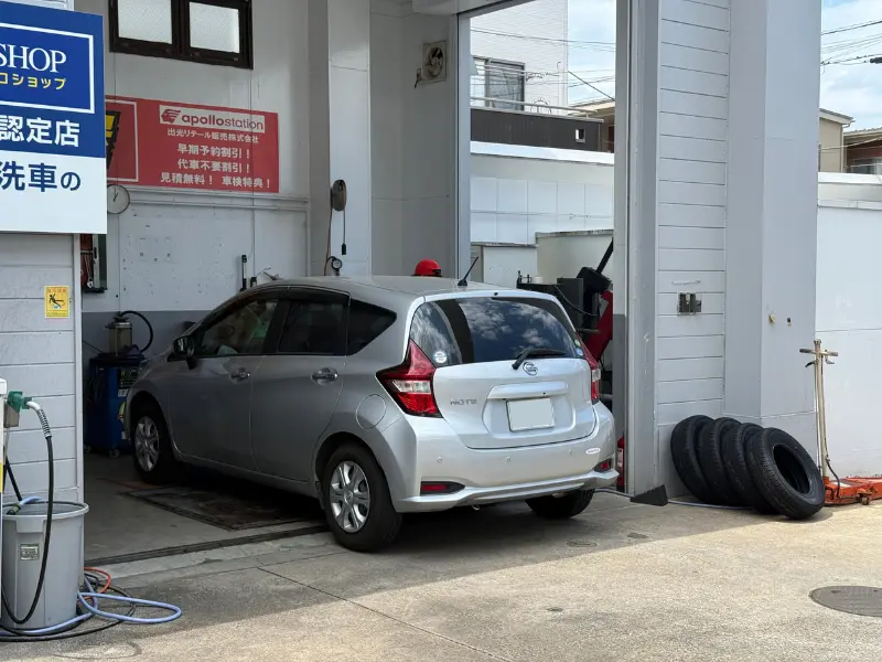 a car parked in a garage　ガソリンスタンドのピットで作業を待つ日産ノートの写真